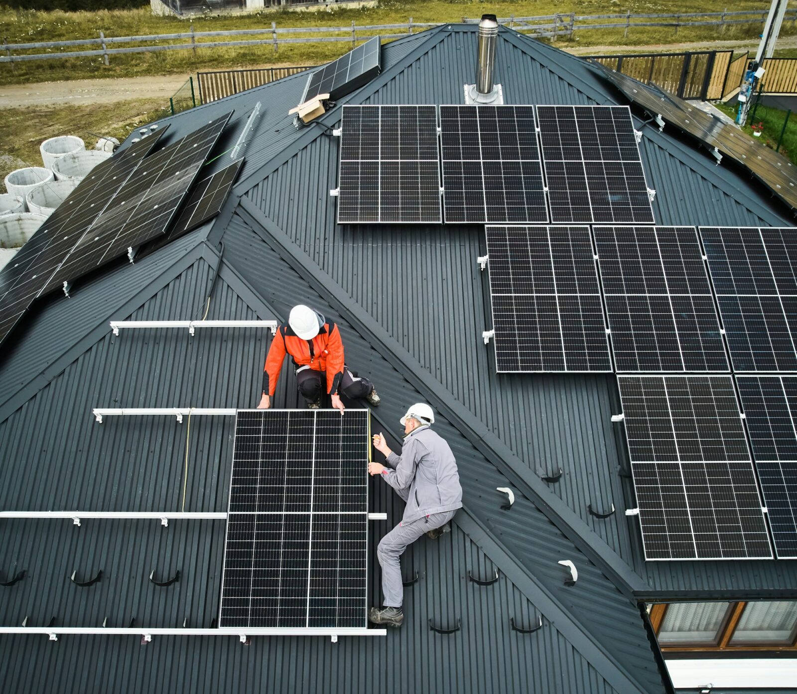 Man worker mounting solar panels on roof of house.